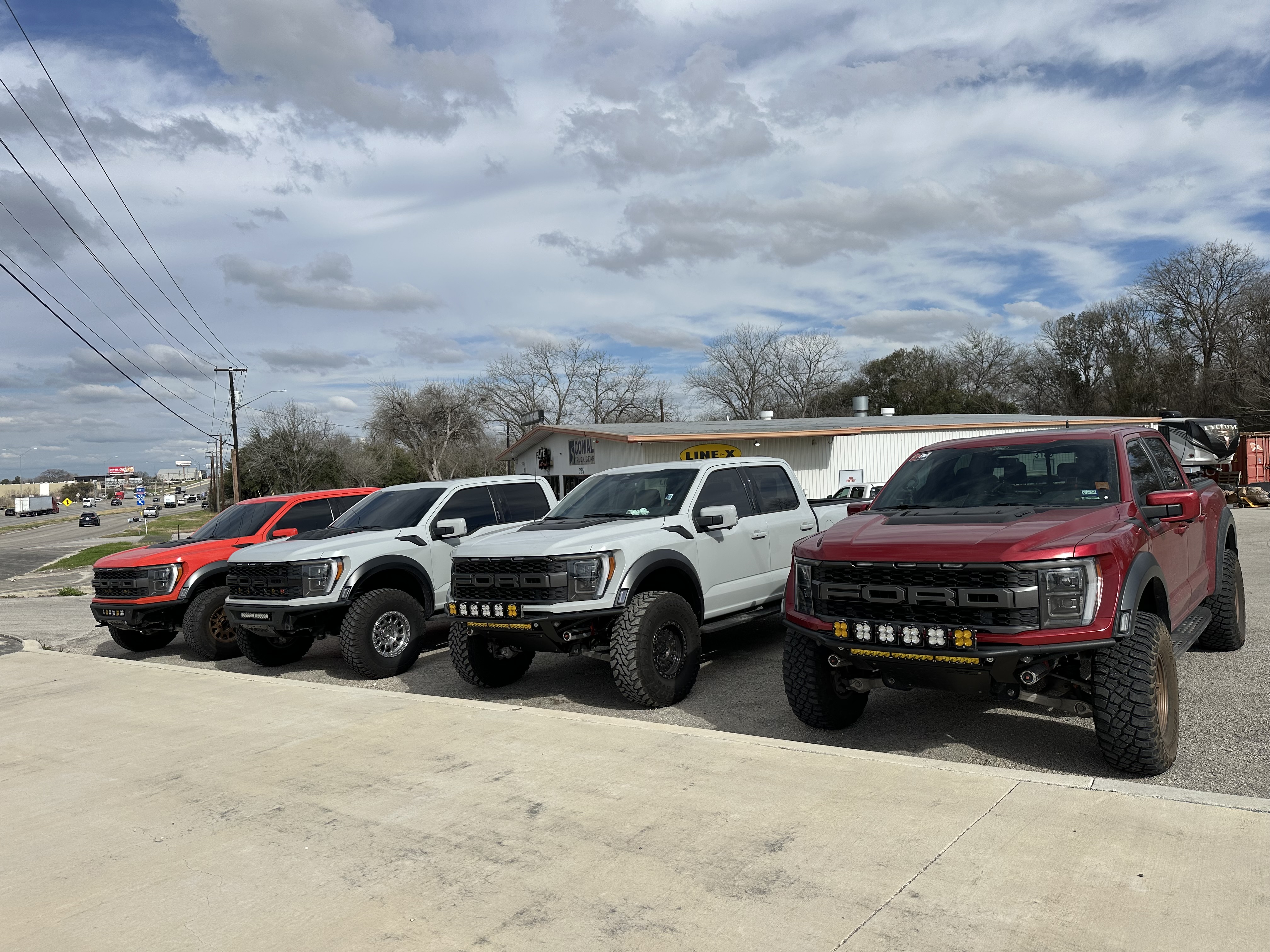 Multiple lifted Ford Raptors lined up at Comal Truck Gear